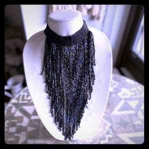 A blue bib necklace cascading 30” down the chest.